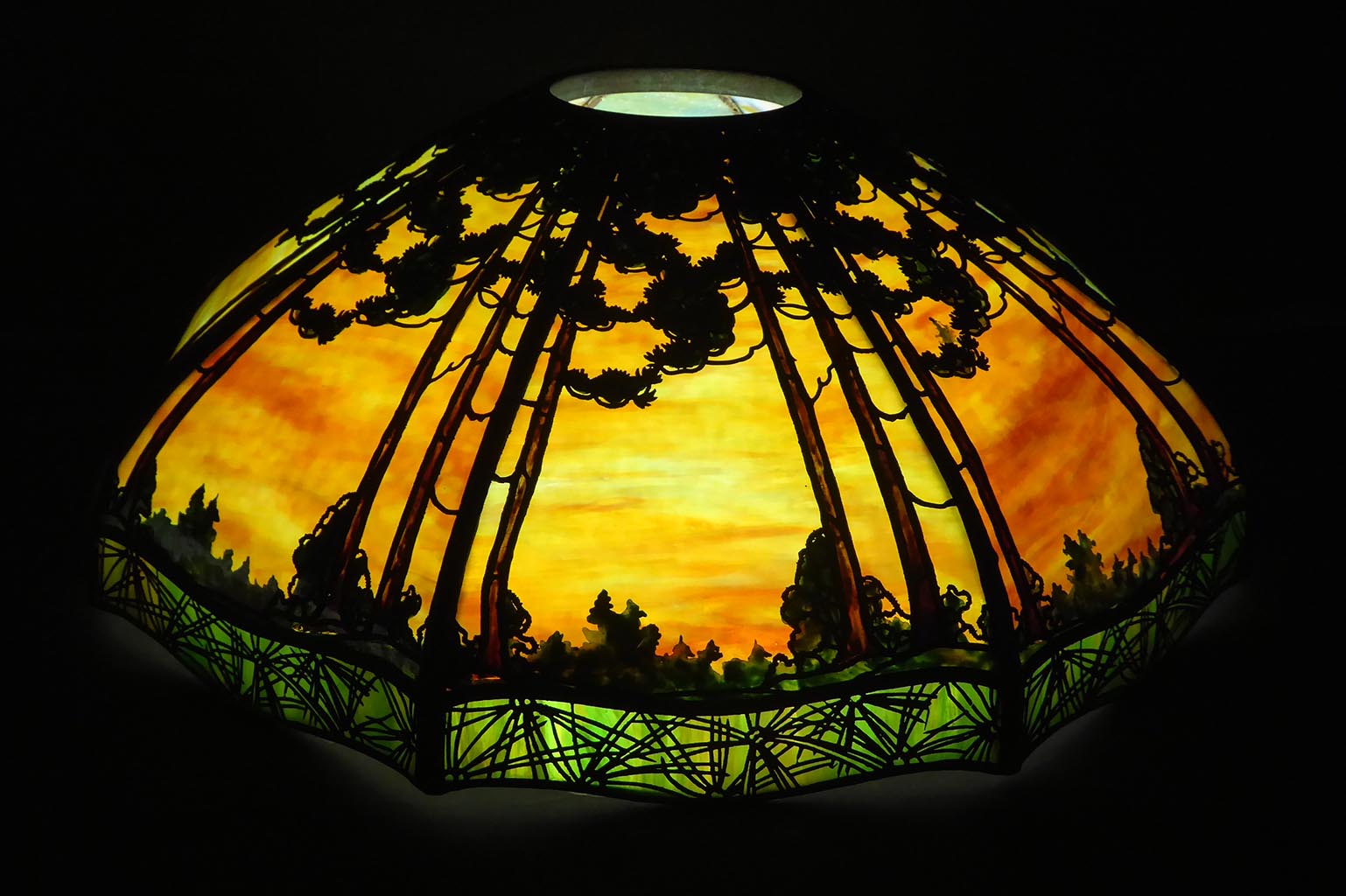 Chinese motif metalwork backed by fiery glass in the lamp body and a medium green glass at the skirt