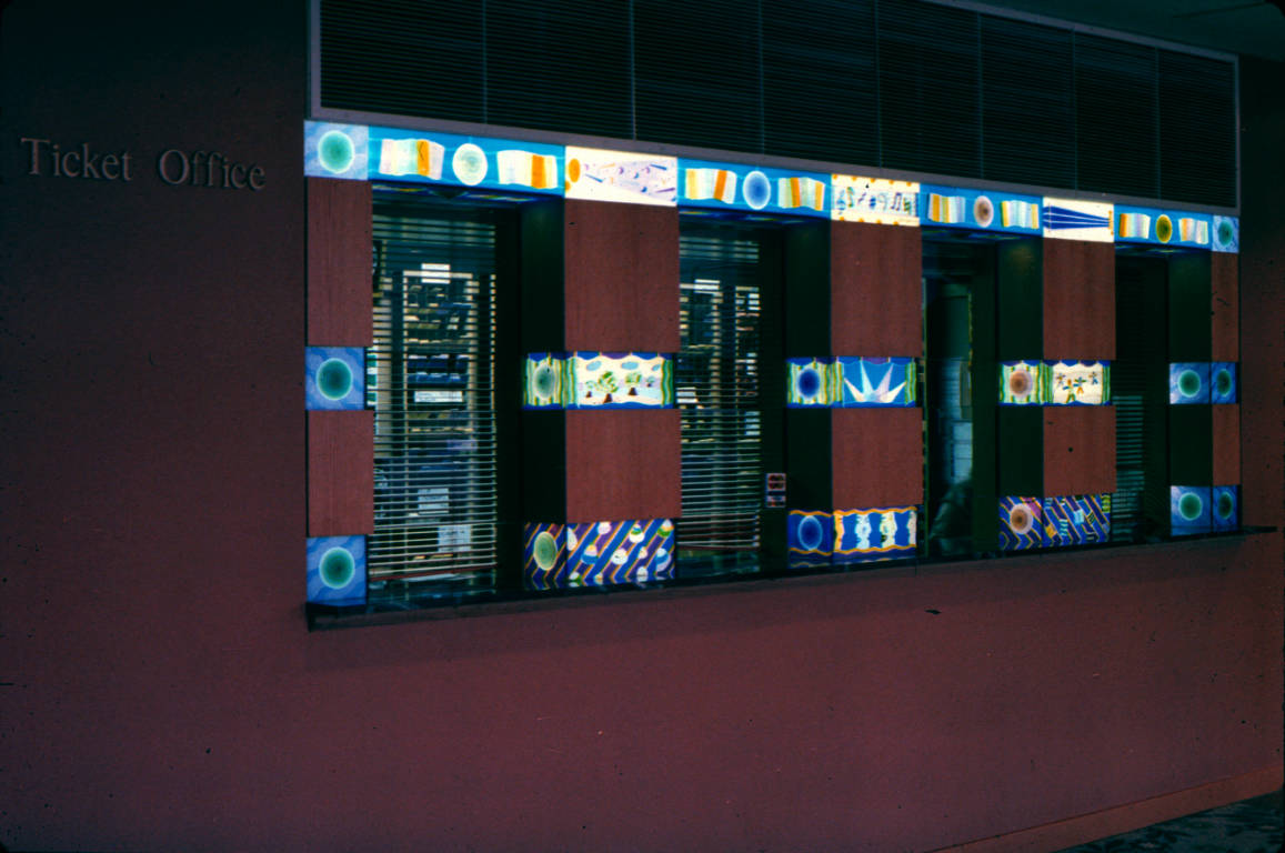 Three illuminated bands of glass crown the windows and borders of the ticket office windows