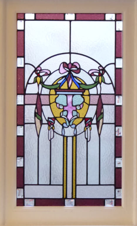 Stained glass with a flowery central motif, a red-amber border with clear glass jewels, and clear textured background glass
