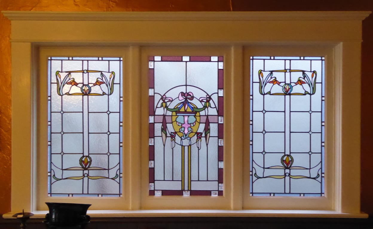 A set of windows, all featuring leaves and flowers, with the center panel being a bit more intricate